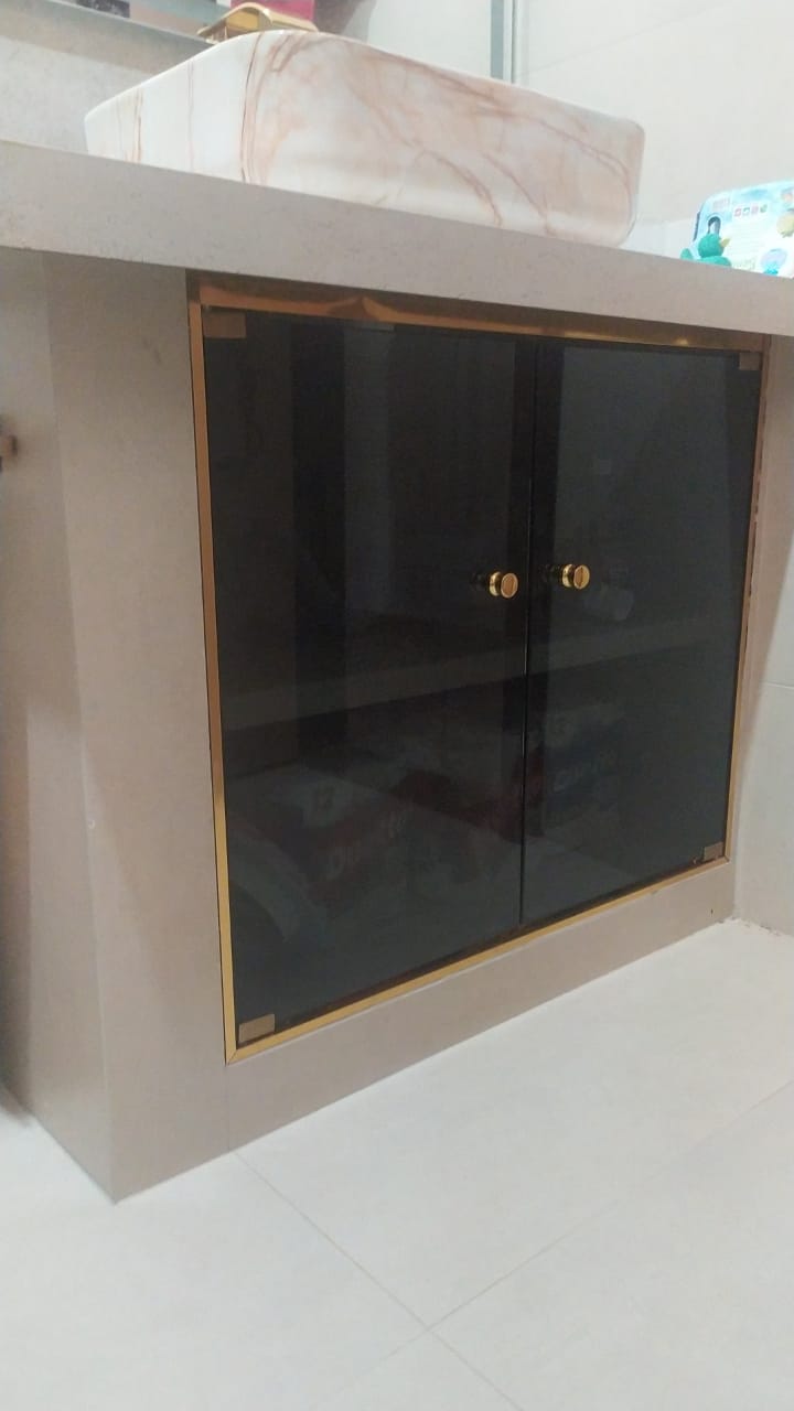 Gabinete de banheiro com portas de vidro fumê e detalhes dourados